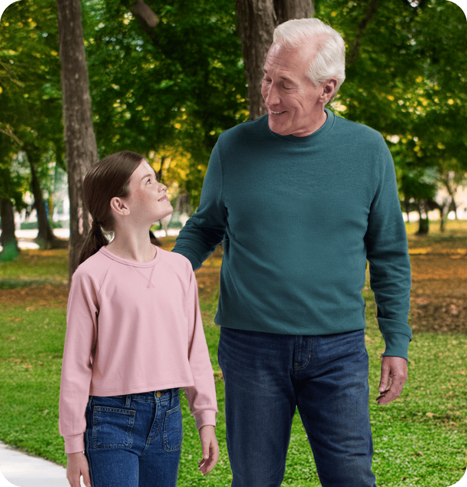 Grandfather walking with granddaughter in the park.